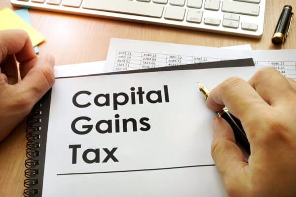 capital gains tax heading on a notepagd with a person's two hands visible